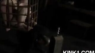 A mistress has a slave tied up in a cage and orders him to fulfill her will