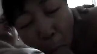 A Chinese woman practices her blowjob skills on her bed