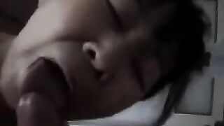 A Chinese woman practices her blowjob skills on her bed