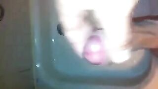 The kid caresses his dick under the shower with his hand until the end