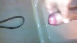 The kid caresses his dick under the shower with his hand until the end