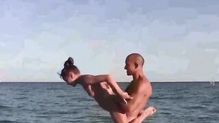 A naked girl is doing acrobatics on the beautiful beach